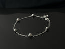Pulseira com bolinhas lisas e pérolas pequenas banhada a prata, medindo 16,5cm.